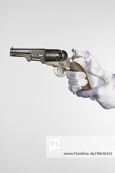 Cropped hands of bride holding handgun against white background