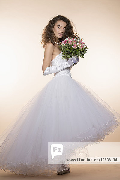 Seitenansicht Porträt der jungen Braut mit Blumenstrauß vor farbigem Hintergrund