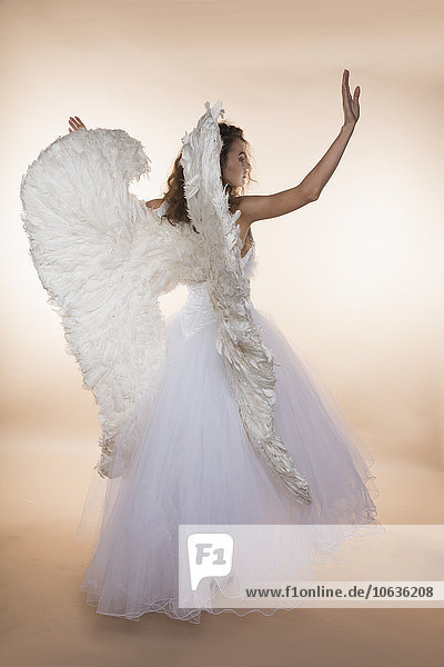 Rear view of bride wearing angel wings while standing against colored background
