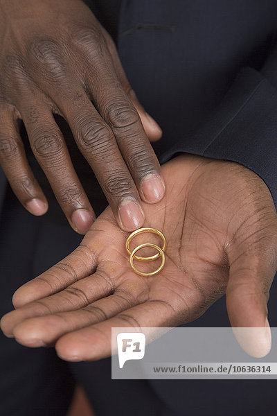 Midsection of man holding wedding rings