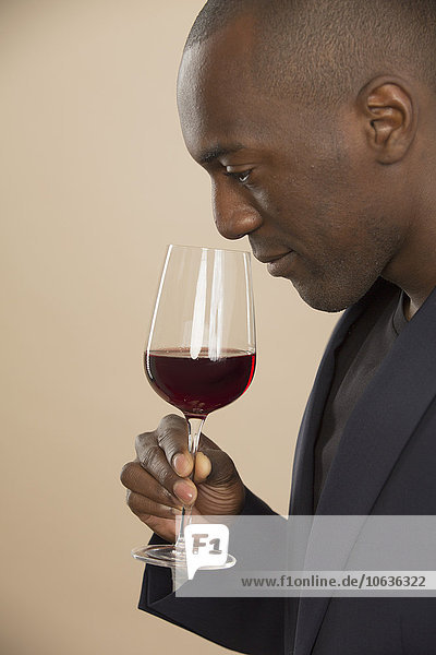 Man smelling red wine against colored background