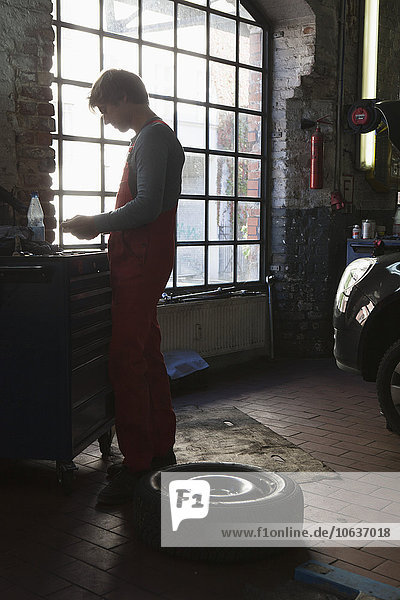 Side view of mechanic standing by window at garage