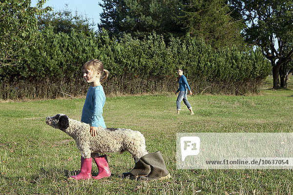Seitenansicht des Mädchens mit Hund in Gummistiefeln auf dem Feld