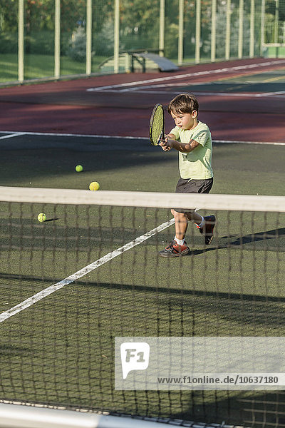 Junge spielt Tennis auf dem Platz