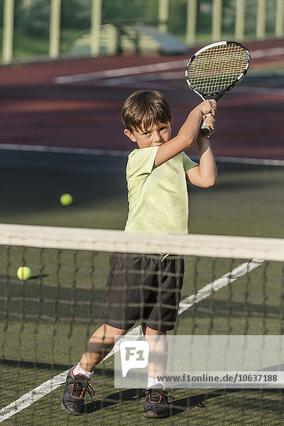 Junge spielt Tennis auf dem Platz bei strahlendem Sonnenschein