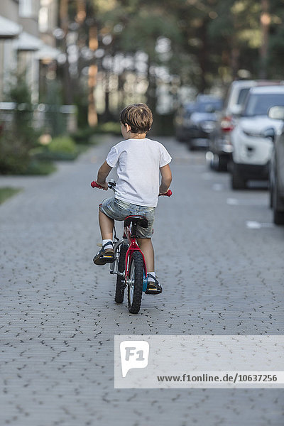 Rear view of boy riding bicycle on street
