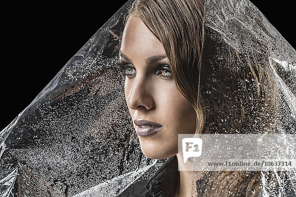Beautiful woman wrapped in plastic against black background