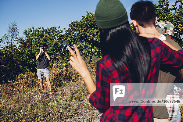 Man photographing friends in forest