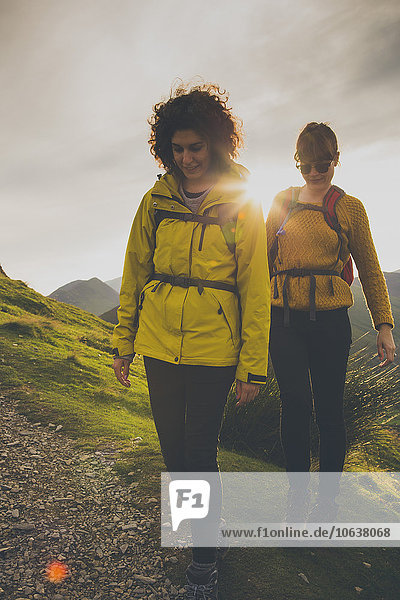 Female friends walking on mountain against sky during sunset