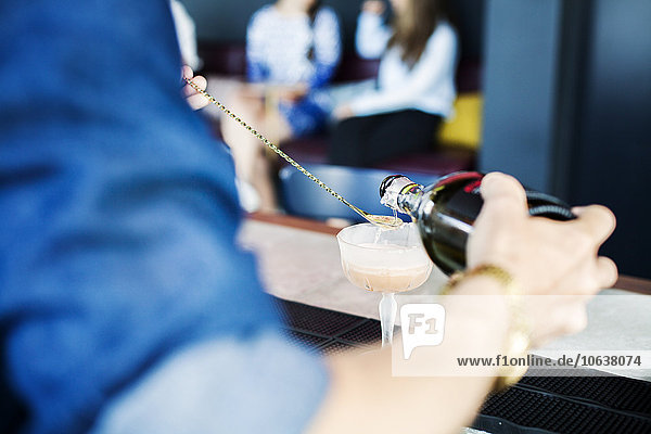 Ausgeschnittenes Bild eines Barkeepers der im Restaurant einen Cocktail in ein Glas gießt