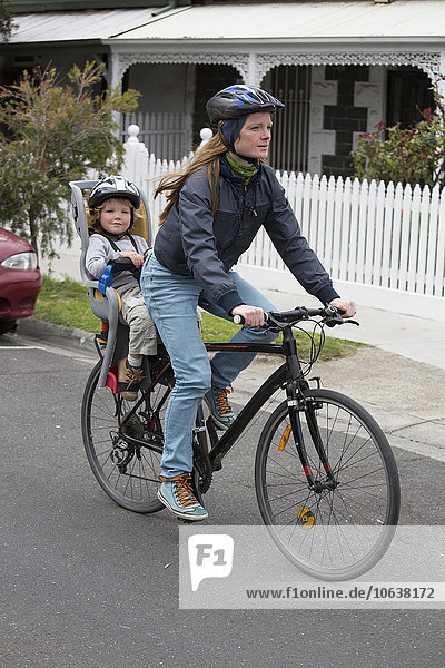 Volle Länge der Mutter beim Radfahren  während der Sohn auf dem Rücksitz sitzt.