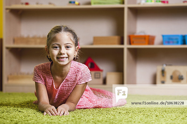 Porträt eines glücklichen Mädchens auf einem Teppich im Klassenzimmer