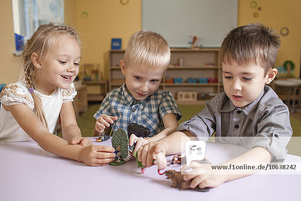 Kinder spielen mit Tierspielzeug am Tisch im Klassenzimmer