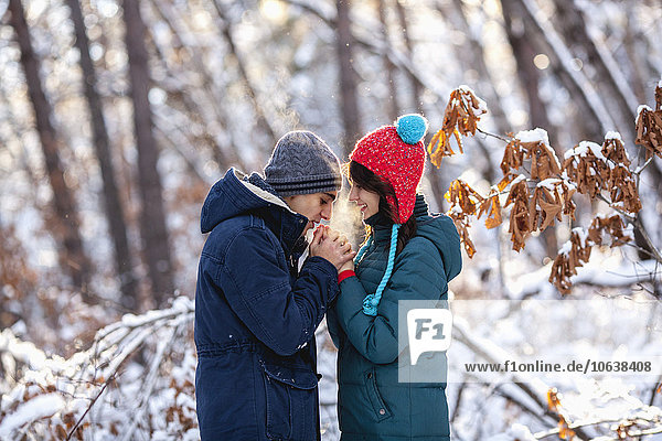 Side view of romantic young couple holding hands during winter