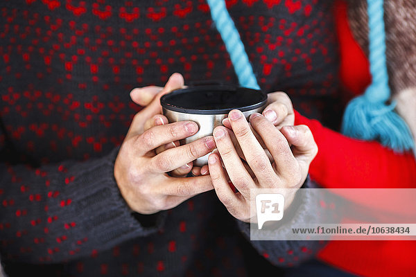 Midsection of young couple holding coffee cup during winter