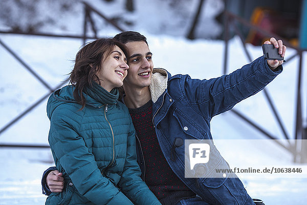 Loving young couple taking selfie through smart phone during winter