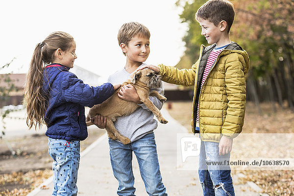 Children playing with dog outdoors