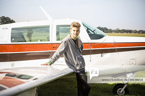 Porträt eines Teenagers  der sich auf ein Privatflugzeug stützt.