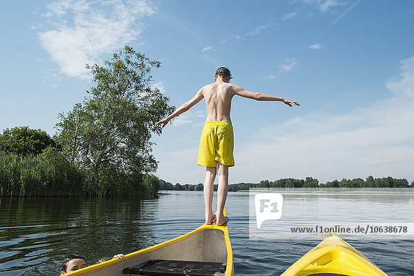 Rückansicht des Jungen  der vom Kanu im See springt.