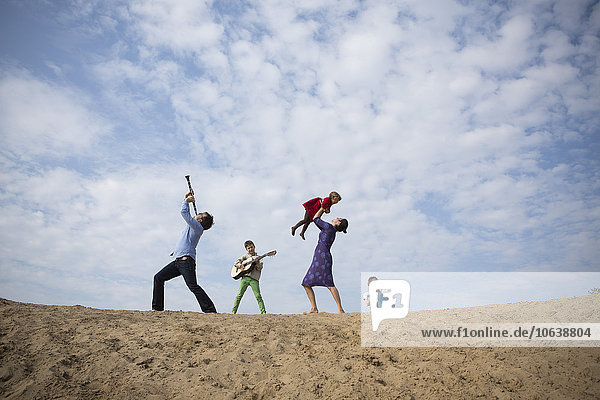 Flachwinkelansicht der Familie auf der Sanddüne gegen den bewölkten Himmel
