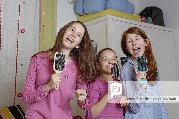 Girls  children singing into hairbrush as microphone  Germany  Europe