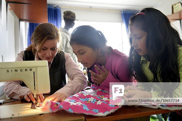Girls and teacher using sewing machine  tailoring  vocational training  Creciendo Unidos social project  Javier Villa  Bogotá  Colombia  South America