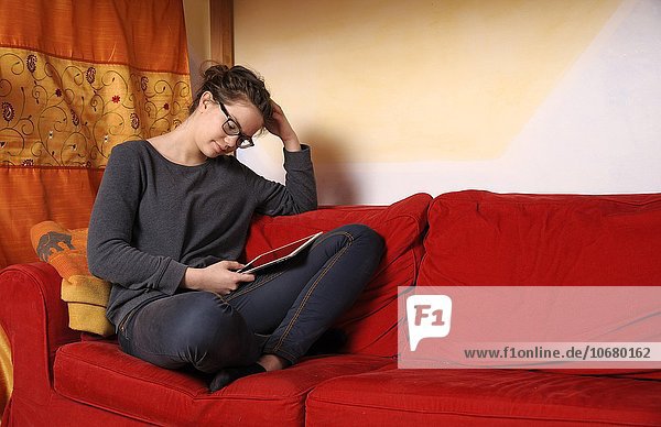 Teenager sitting with an i-Pad on a couch  Germany  Europe