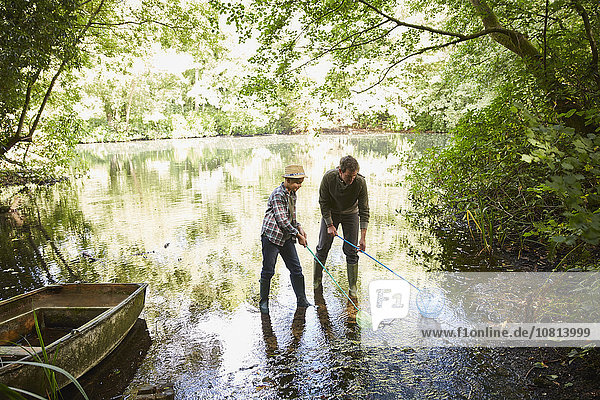 Vater und Sohn fischen mit Netzen im Waldteich