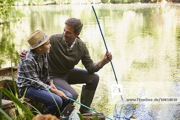 Vater und Sohn fischen mit Netzen im Teich