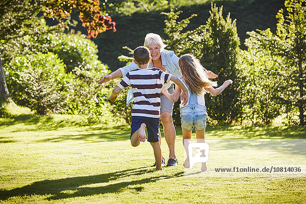 Enkelkinder rennen zur Großmutter im sonnigen Garten