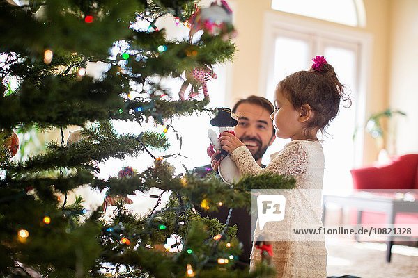 Vater und Tochter schmücken den Weihnachtsbaum