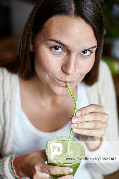Woman drinking green smoothie with straw