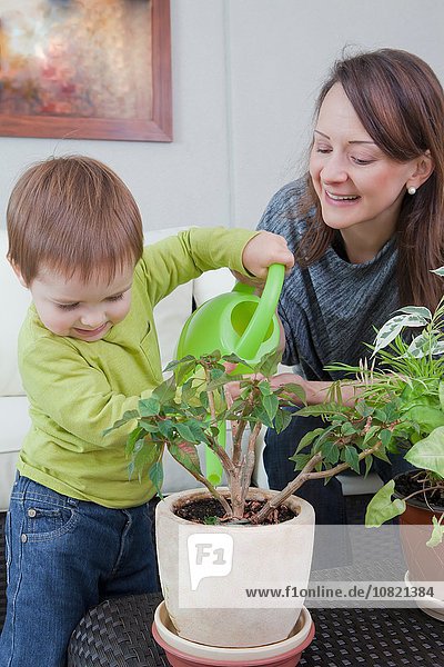 Mother and son watering plant at home
