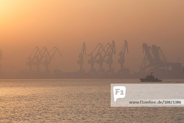 Kräne im Hafen bei Sonnenaufgang