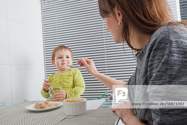 Mutter füttert Sohn am Esstisch