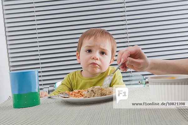 Mutter füttert Sohn am Esstisch