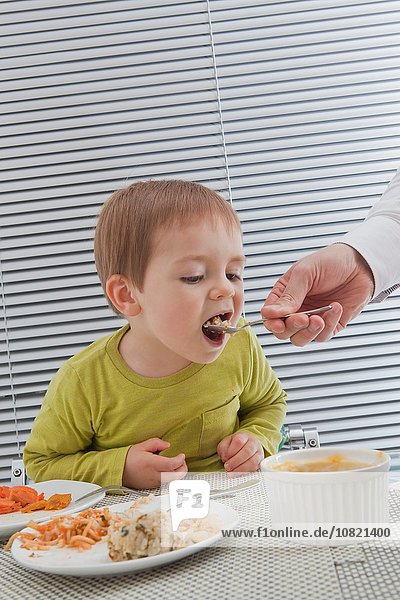 Father feeding son at dining table