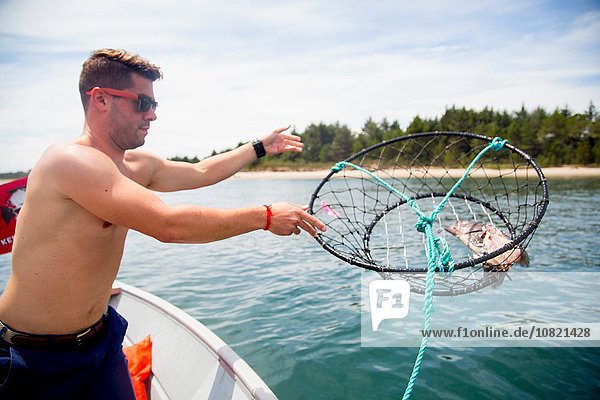 Mid adult man throwing baited crab trap from fishing boat  Nehalem Bay  Oregon  USA