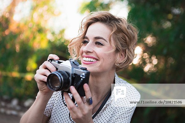 Mittlere erwachsene Frau beim Fotografieren  draußen  lächelnd