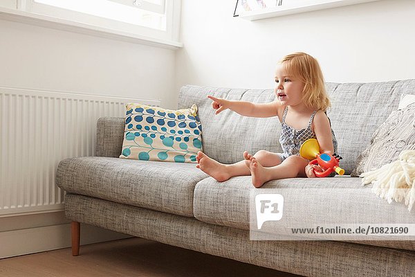Kleinkind spielt mit Spielzeugtrompete auf Sofa