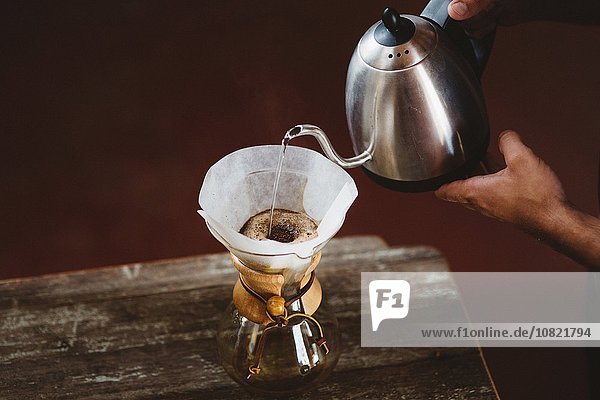 Mann gießt Wasser in die Filterkaffeemaschine
