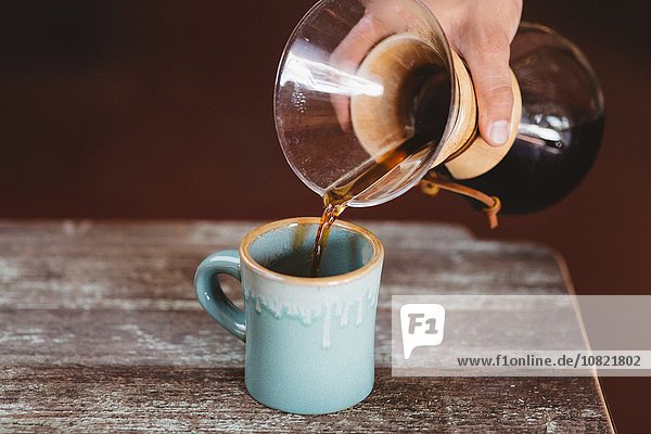 Mann gießt Kaffee aus der Filterkaffeemaschine
