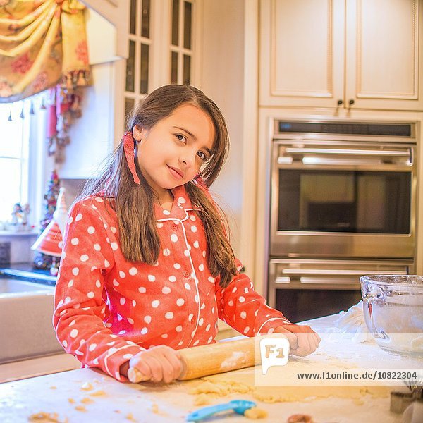 Portrait of young girl in kitchen  using rolling pin