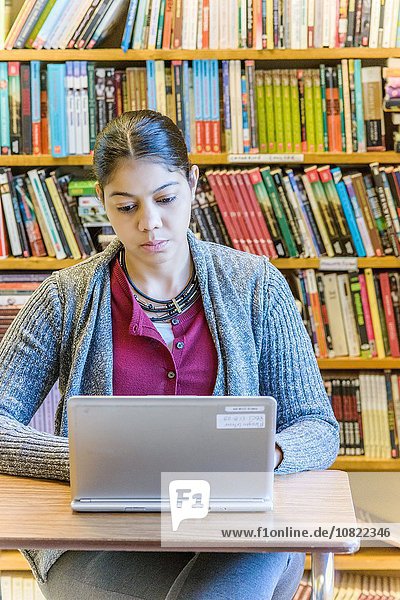 Reife Studentin mit Laptop in der Bibliothek