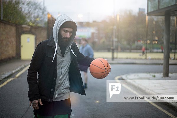 Ein erwachsener Mann  der die Straße entlang läuft und Basketball spielt.