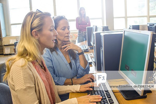 Zwei Frauen suchen Computerdaten für Bücher in der Bibliothek