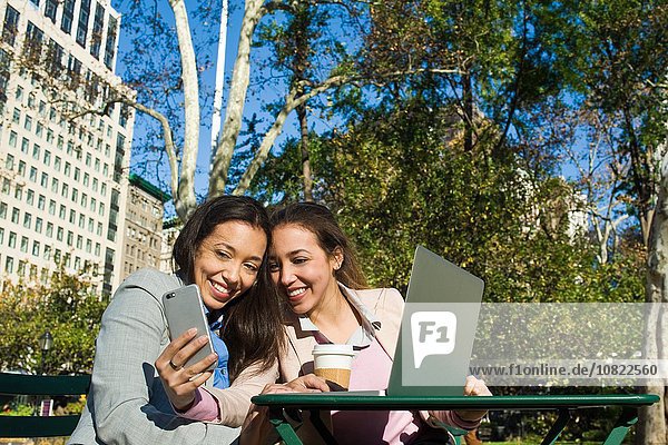 Junge erwachsene weibliche Zwillinge nehmen Smartphone Selfie im Stadtpark