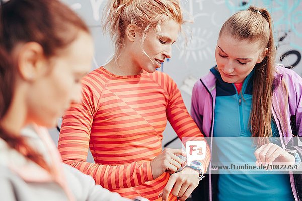 Drei Läuferinnen prüfen die Zeit auf smartwatch