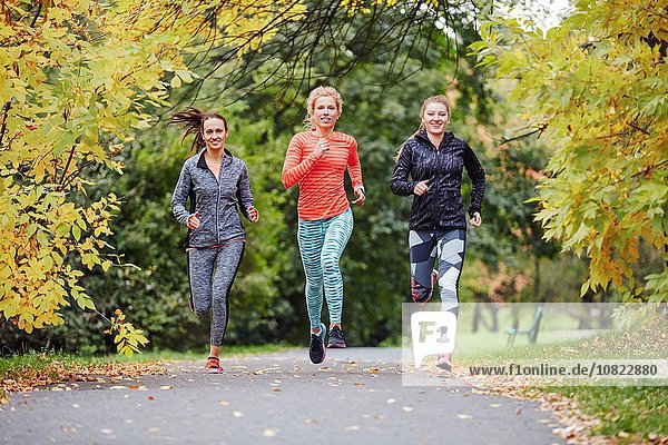 Three female runners running along park path