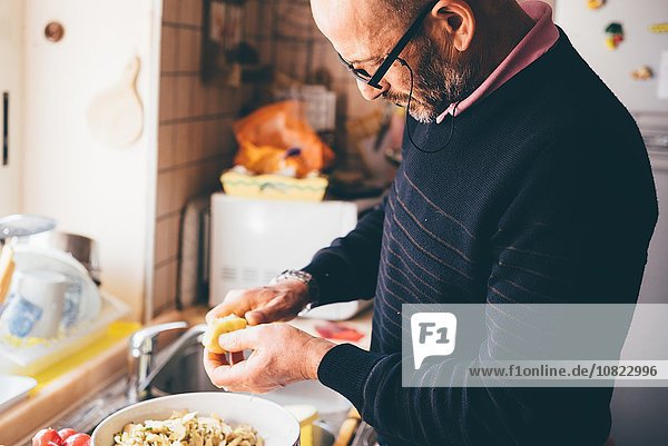 Senior Mann beim Schneiden von Artischocken in der Küche
